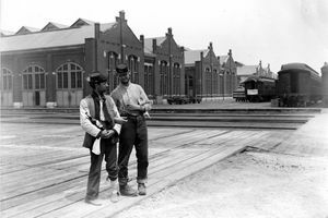 Dvaja opravári stoja pri budove Pullman a trénujú autá so zamknutými ramenami a fľašou likéru počas štrajku z roku 1894 v Chicagu, Pullman Strike