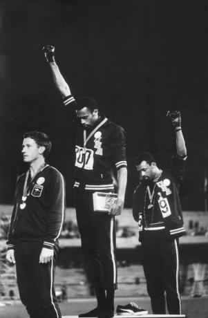 Fotografia afrických amerických členov amerických tímov tímov Tommie Smith a John Carlos zdvíhajú päty čiernej moci v rukaviciach ako protest proti občianskym právam počas slávnostného odovzdávania medailí na olympijských hrách v roku 1968 v Mexico City