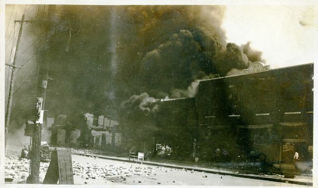 Poškodený majetok a dym vychádzajúci z budov po masakre v Tulse, Tulsa, Oklahoma, jún 1921.