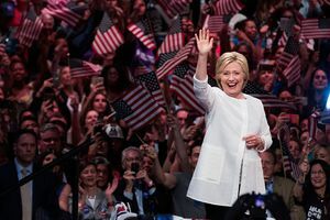 Hillary Clintonová máva pred davom ľudí mávajúcich vlajkami USA