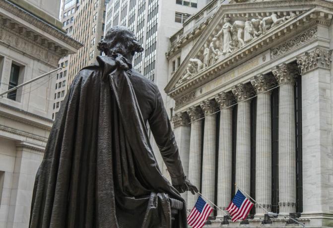 Socha Georga Washingtona sa pozerá smerom na budovu New York Stock Exchange na Broad Street z Národného pamätníka Federal Hall na Wall Street v New Yorku.