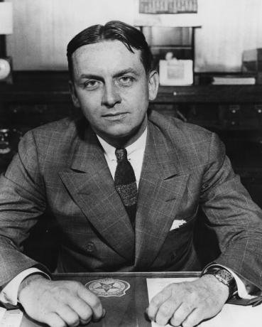 Agent FBI Eliot Ness, ktorý sedel pri stole, c. 1930.