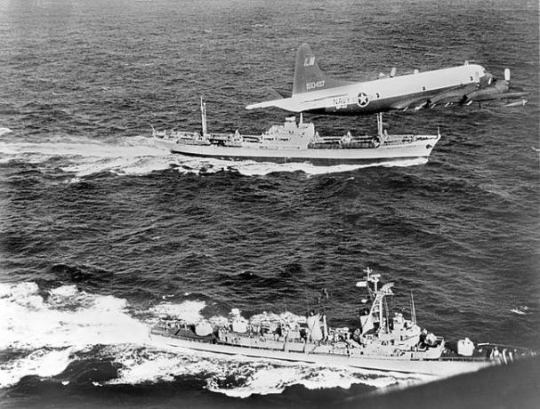 Sovietska nákladná loď Anosov vzadu sprevádzaná námorným lietadlom a torpédoborcom USS Barry, keď opúšťa Kubu počas kubánskej raketovej krízy v roku 1962.