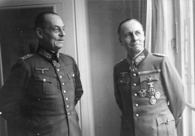 Gerd von Rundstedt a Erwin Rommel v nemeckých vojenských uniformách stojacich pri okne.