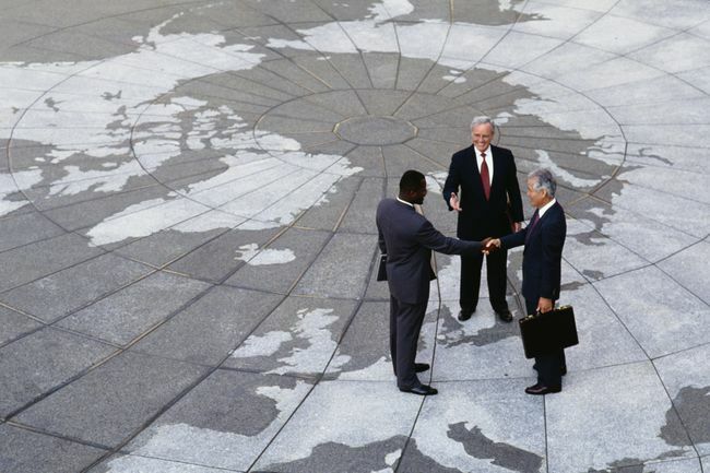  Ekonomický regionalizmus: Podnikatelia si podávajú ruky na mape zemegule.