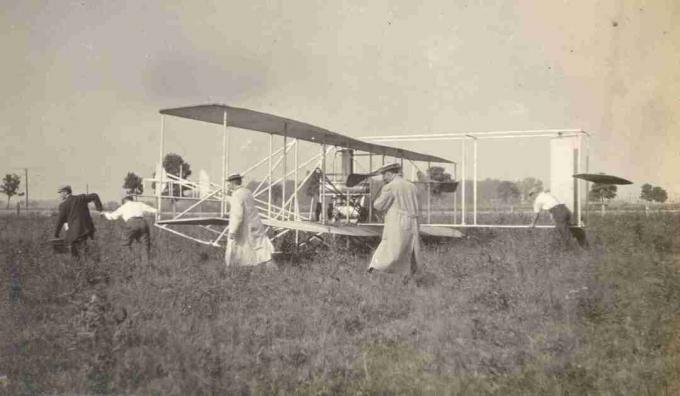 Študenti pohybujúci leták Wright B na letisku Huffman Prairie Flying Field