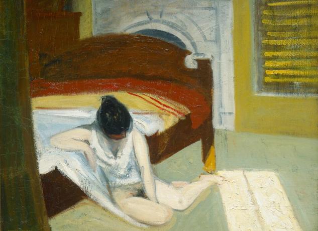 Mladá žena sedí napoly nahá na podlahe vedľa postele v tmavej miestnosti.