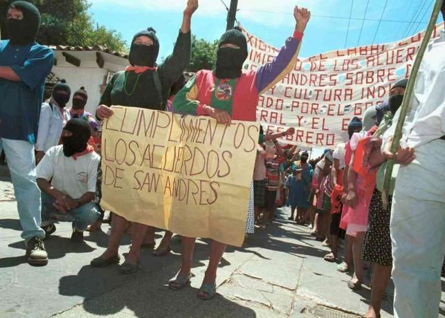 Dve ženy sú označené znakom, ktorý vyzýva vládu, aby dodržiavala San Andrésské dohody