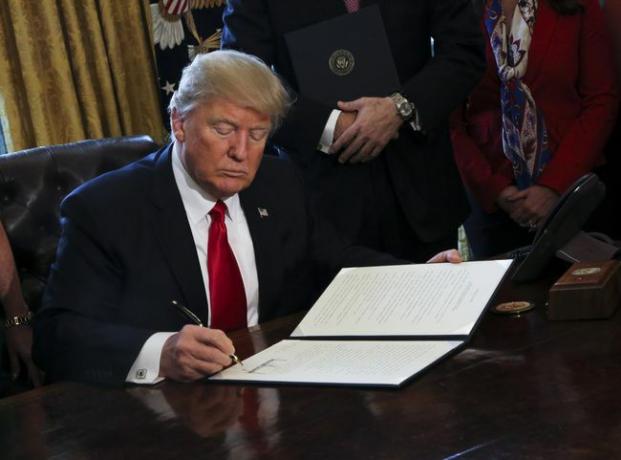 Americký prezident Donald Trump podpisuje exekutívne príkazy vrátane príkazu na revíziu Dodd-Frank Wall Street s cieľom zrušiť finančné regulácie z Obamovej éry.